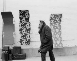 Smoker in cold weather walks past lawn furniture hanging on a wall